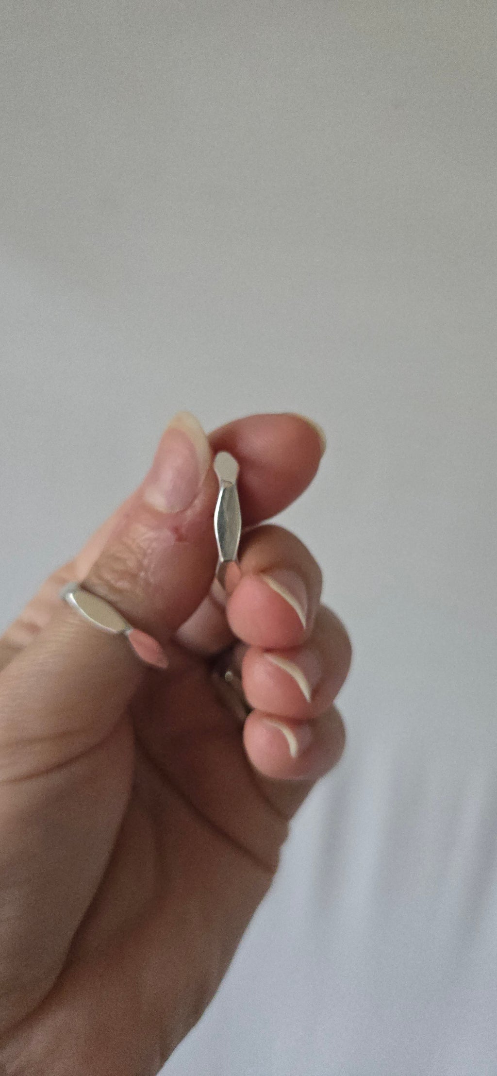 hand holding a silver ring against white backdrop